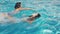 Two happy teenagers, a brother and sister, are swimming in a race in the pool. Slow motion. steadicam shot. 4k