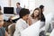 Two happy women discuss work at computer in open plan office