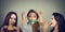 Two happy women eating hamburgers looking at stressed girl with measuring tape around her mouth.