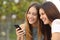 Two happy women friends sharing a smart phone