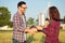 Two happy young female and male farmers or agronomists shaking hands in a wheat field