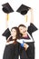 Two happy young graduate students holding hats and diploma