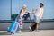 Two happy young tourists holding hands and running in front of an airport terminal.