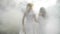 Two happy young women spinning and dancing in the forest through smoke in slow motion -