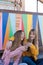 Two happy young women toast with drink with a multicolored background