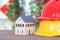 Two hard hats of different colors and a small house model