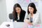 Two hardworking asian young female entrepreneurs working together on a laptop computer reading the screen with serious face