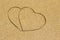 Two heart shape engraved in a wet sandy beach