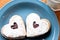 Two heart-shaped cookied on a blue plate with milk