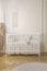 Two heart shaped pillows placed on baby crib standing in white room interior with macrame on wall and herringbone parquet