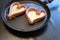 Two heart-shaped sausages lie in the pan. Roasting sausages cut lengthwise. Thick albumen poured inside. Cooking a meal. Love,