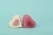Two heart sheaped pink petit four candy`s on a turquoise backgro