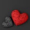 Two hearts of black and red handmade woven from many threads lie on a black background. 3D illustration