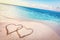 Two hearts drawn on sand of a tropical beach at sunset.