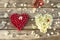 Two hearts of raspberries and white small flowers on a wooden background. The Little Heart of tape