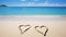Two hearts on a sandy beach against a blue sea background