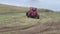 Two helmeted racers ride down a mountain in a red buggy