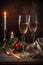 Two high glasses of champagne with a bowl of strawberries and candles on wooden table, shot in low key. Romantic dinner atmosphere