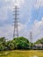 Two high voltage power poles located among the trees along the large ponds and restaurants in city,  High voltage electric poles