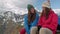 Two hikers relaxing on top of hill and enjoying sunrise over the valley