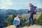 Two hikers at viewpoint in the mountains enjoying beautiful view of the valley with a lake.