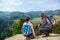 Two hikers at viewpoint in the mountains enjoying beautiful view of the valley with a lake.