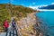 Two hikers and walking path at Lago Argentino near huge Perito Moreno glacier in Patagonia in golden Autumn, South America