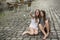 Two hilarious teenage girls are doing selfie on the phone sitting on the pavement.