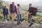 Two hipster couples with backpacks hiking in the mountains during long trip. Happy caucasian group of travelers have an