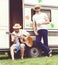 Two hipster friends chilling outdoors. Playing guitar, drinking.