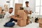 Two hispanic men couple smiling confident packing book cardboard box at new home