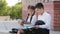 Two hispnic children students pupils sitting outdoors with books reading after class. Girl reads book sad boy showing