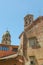 Two historic brick churches with towers in contrast to more modern orange house in Siena, Italy, Europe