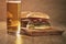 Two homemade burgers on olive board on oak table with beer