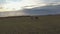 Two horsewomen riding horses across the field at sunset.