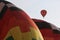 Two hot air balloons inflate side-by-side as a third flies in the background