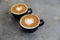 Two hot cups of cappucino on concrete background. Heart shape art latte symbol of love