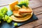 Two hot grilled or fried sandwich with cheese and green grapes on black slate cheeseboard on wooden table