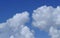 Two huge white cumulonimbus clouds on the light blue sky