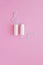 Two hygienic tampons on a pink background.