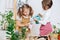 Two immersed curious little girls watering seedling in a cup with little can