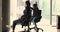 Two Indian office employee riding seated on chairs at workplace