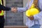 Two individuals shaking hands in front of a construction site as a gesture of agreement and partnership