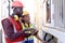 Two industrial African worker engineer man and woman wear safety vest and helmet, checking instrument panel button at