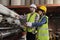 Two industrial workers use a laptop to check a paper manufacturing machine