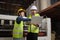 Two industrial workers use a laptop to control a paper manufacturing machine