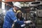 Two industrial workers work with metalwork machines in manufacturing factory