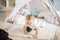 Two infant boys sit on carpet in tent, have fun and playing with toys at home