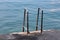 Two inox handrails for easier entrance from concrete beach to calm blue sea