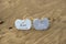 Two inscribed wooden love hearts in the quick sand